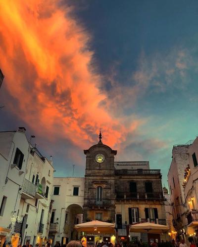 a clock tower on a building with a cloudy sky at Lamia Nina in Cisternino