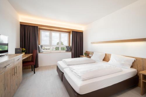 Schlafzimmer mit einem Bett, einem Schreibtisch und einem TV in der Unterkunft Snooze Apartments in Holzkirchen