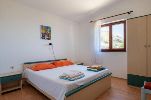 a bedroom with a bed with orange pillows and a window at Barba Damir in Pag