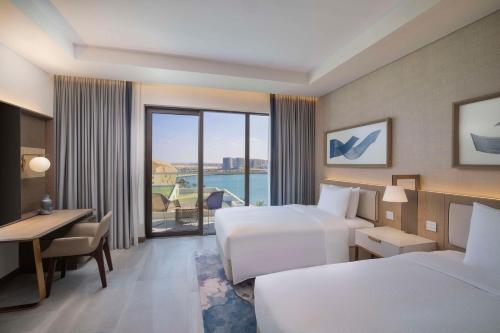 a hotel room with two beds and a desk at Hilton Abu Dhabi Yas Island in Abu Dhabi