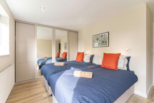 três camas num quarto com lençóis azuis e almofadas laranja em Stylish 2 Bedroom Apartments in Derby em Derby