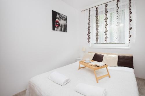 a white room with a bed and a table at Elegant Apartment Myśliwskie Wzgórze in Gdańsk by Renters in Gdańsk