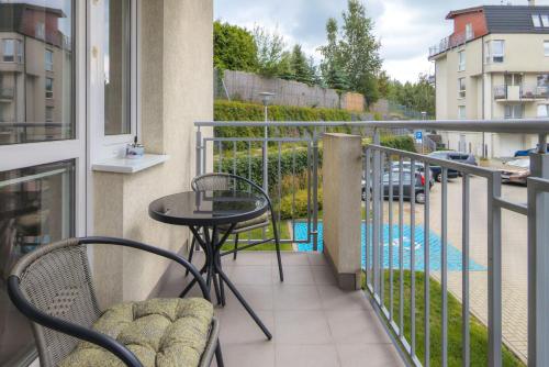 a balcony with a table and chairs and a pool at Elegant Apartment Myśliwskie Wzgórze in Gdańsk by Renters in Gdańsk