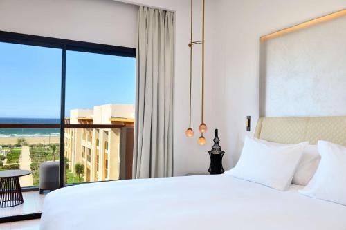 a bedroom with a white bed and a large window at Hilton Taghazout Bay Beach Resort & Spa in Taghazout