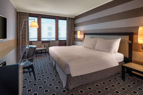 a hotel room with a large bed and a desk at Hilton Geneva Hotel and Conference Centre in Geneva