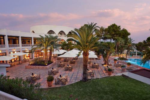 a resort with tables and palm trees and a pool at Hilton Mallorca Galatzo in Paguera