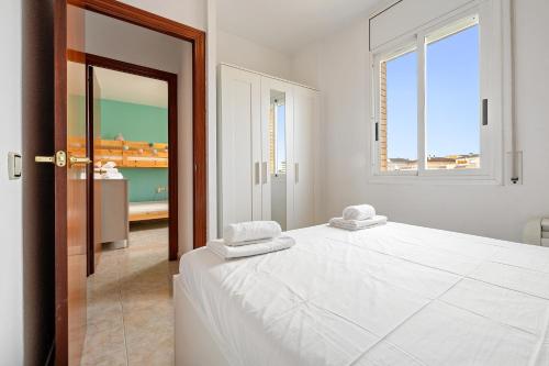 クニットにあるApt en Cunit con piscina compartidaの白いベッドルーム(ベッド1台、窓付)