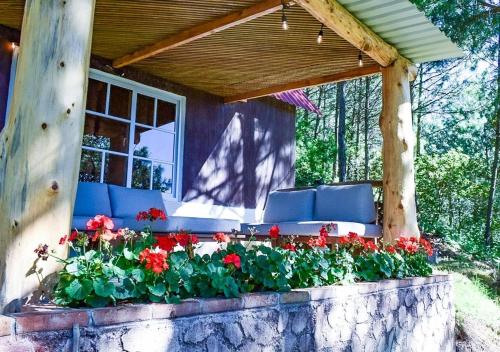 a porch with red flowers on a stone wall at Finca Chuchiyá cabañas Tecpan in Tecpán Guatemala