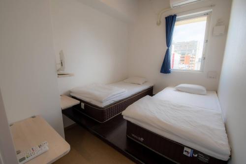 two beds in a small room with a window at Chura Cabin Kokusai-Dori in Naha