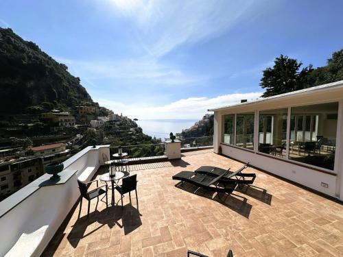 a balcony with chairs and tables on top of a building at Il Canneto in Positano