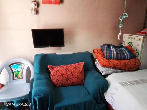 sala de estar con sofá azul y TV en Cosy budget Single room en Nairobi