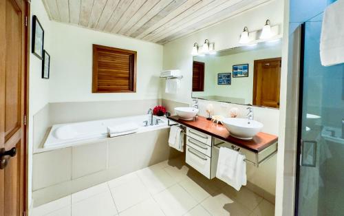 een badkamer met 2 wastafels, een bad en een spiegel bij The Hideaway Suite 1512 Pool and Sea views in Gaynors