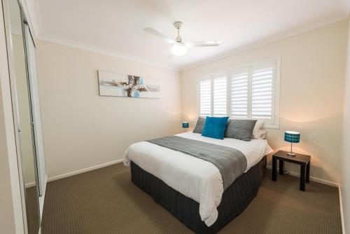 a bedroom with a bed with blue pillows and a window at Bottletree Apartments on Garget in Toowoomba
