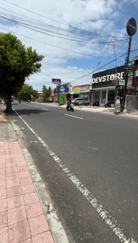 a motorcycle driving down a street in front of a store at Royen Balinese Family Guest House- Traditional Batuan Homestay in Sukawati