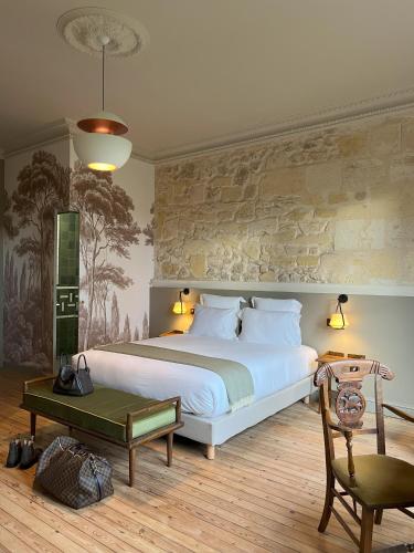 - une chambre avec un grand lit blanc et un mur en pierre dans l'établissement Domaine de Lézin, à Saint-Germain-du-Puch