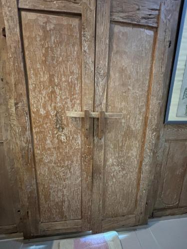 a wooden door in a room next to a window at Royen Balinese Family Guest House- Traditional Batuan Homestay in Sukawati