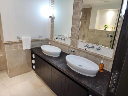 a bathroom with two sinks and a large mirror at Whispering Pines Jumeirah Golf Estates by Golden Casa in Dubai