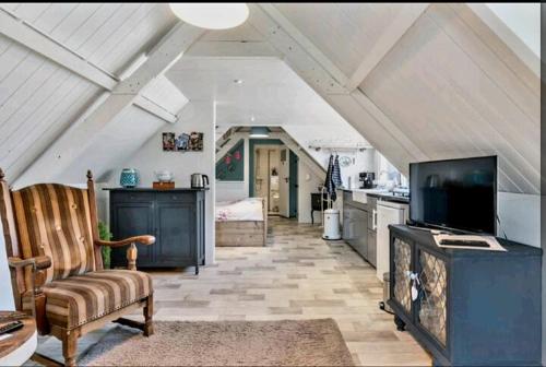 a living room with a tv and a kitchen at De Oude Smederij voor 2 personen in 't Veld in De Leijen