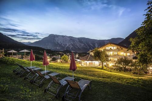 a row of chairs and umbrellas on a lawn with a building at Aktiv Panoramahotel Daniel in Sautens