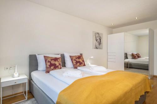 a white bedroom with a bed and a mirror at Cocoon am Schloß Top 2 in Lochau