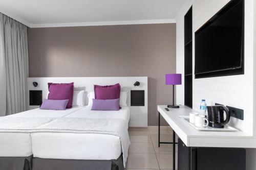 a bedroom with a white bed and purple pillows at Alexandre La Siesta in Playa de las Americas