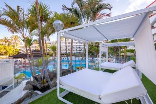 a white canopy bed on a balcony with a swimming pool at Alexandre La Siesta in Playa de las Americas