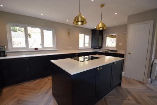 a kitchen with black cabinets and a white counter top at Crann Mhor Holiday Home in Lochgoilhead
