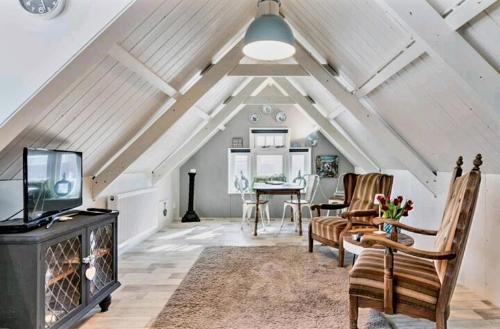 an attic living room with a tv and a table at De Oude Smederij voor 2 personen in 't Veld in De Leijen