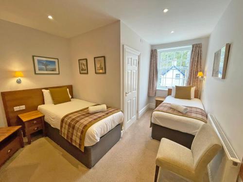 a bedroom with two beds and a chair in it at The Glengower in Aberystwyth