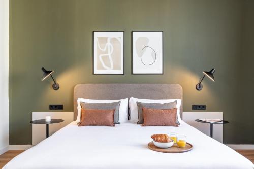 a bedroom with a white bed with three pictures on the wall at Aspasios Rambla Catalunya Apartments in Barcelona