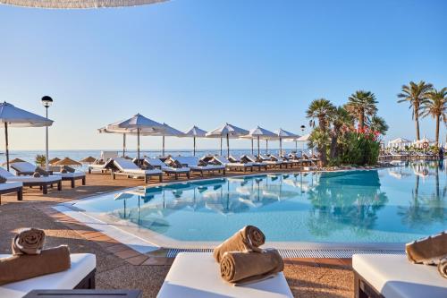 una piscina sulla spiaggia con sedie e ombrelloni di AluaSoul Menorca - Adults Only a S'Algar