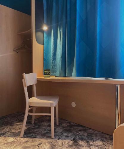 a chair sitting next to a desk with a blue curtain at B&B HOTEL Amiens Centre Cathédrale in Amiens