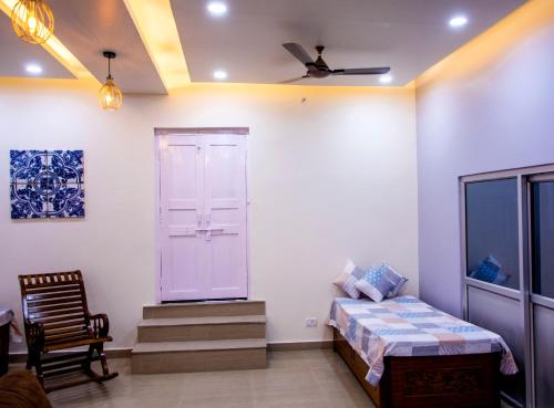 um quarto com uma cama, uma cadeira e uma janela em Gooseberry Garden em Ayodhya