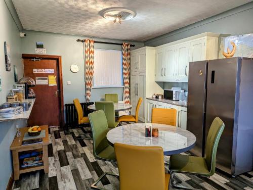 een keuken met een tafel en stoelen en een koelkast bij Fairy Bridge Lodge in Bundoran