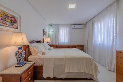 um quarto com uma cama e uma mesa com um candeeiro em Condomínio Mykonos #400 - Apê Deluxe em Fortaleza por Carpediem em Fortaleza