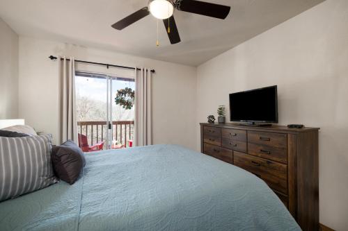 a bedroom with a bed and a flat screen tv at Family and Pet friendly ground level Condo, 4 mins to Silver Dollar City, Amazing Ozark Mountain Views in Branson
