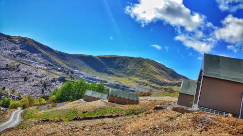 a building on a hill with mountains in the background at Llechwedd Glamping in Blaenau-Ffestiniog