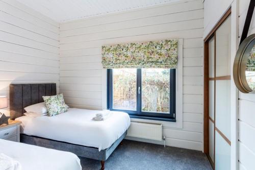 een slaapkamer met 2 bedden en een raam bij Roydon Marina - Lodge 1 - Hot Tub in Roydon