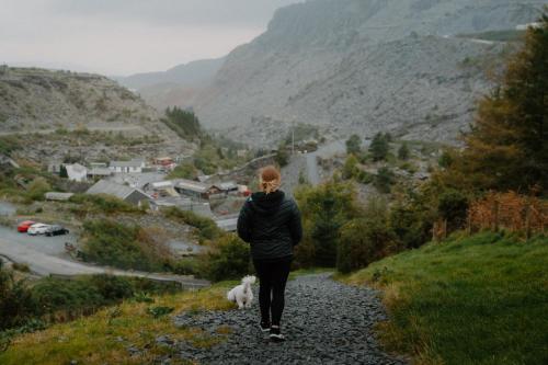 a woman walking down a gravel road with a dog at Llechwedd Glamping in Blaenau-Ffestiniog