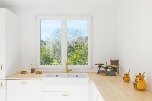 une cuisine avec des placards blancs et une grande fenêtre dans l'établissement LA PROVENCE Piscine privée, Pétanque et Barbecue, aux Arcs-sur-Argens