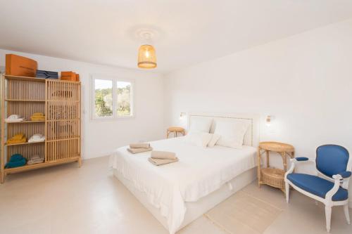- une chambre blanche avec un lit et deux chaises bleues dans l'établissement LA PROVENCE Piscine privée, Pétanque et Barbecue, aux Arcs-sur-Argens