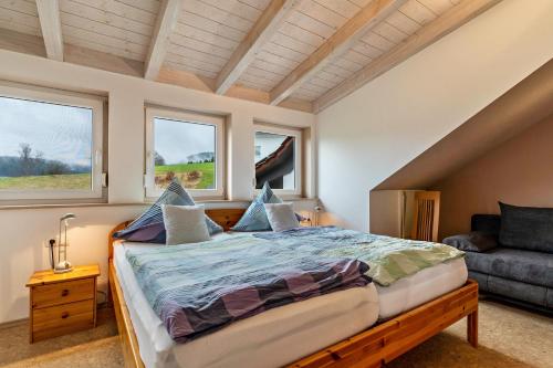 een slaapkamer met een bed, een bank en ramen bij Ferienwohnung Sonnenschein in Baiersbronn