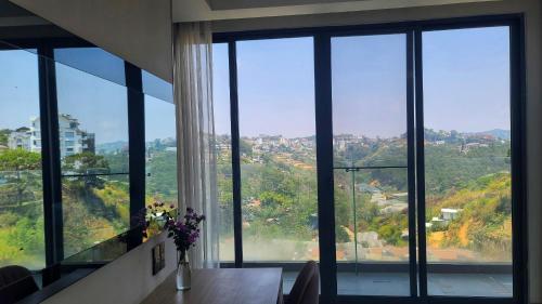 a room with glass windows and a table with flowers at The Luxe Da Lat in Da Lat