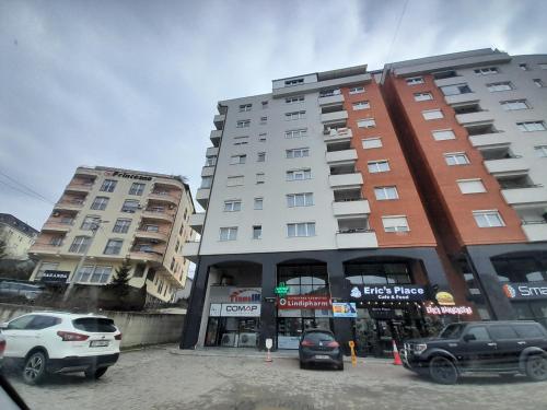 two tall buildings with cars parked in a parking lot at Gray Apartment 1 Pristina in Pristina