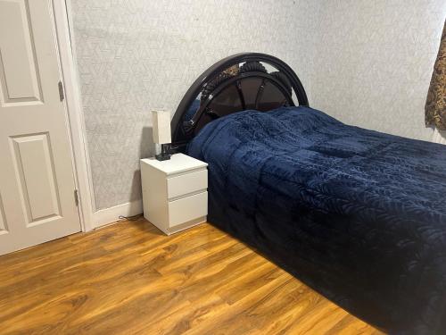 sypialnia z łóżkiem z niebieskim kocem i stolikiem nocnym w obiekcie London Holiday Home w Londynie