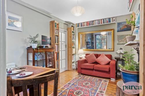 a living room with a red couch and a table at Parea Living - Cosy 1-Bed Artistic Flat at Newington Green in London