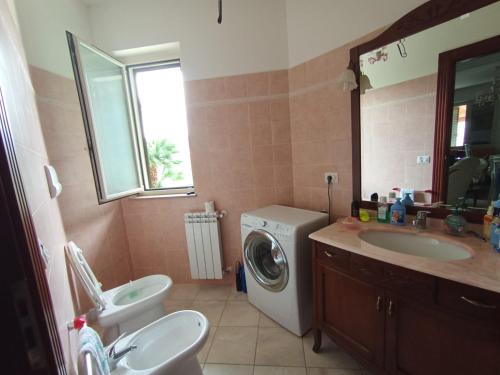 a bathroom with a washing machine and a sink at Villa Framaca in Furnari
