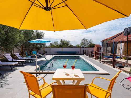 a pool with a table and chairs and an umbrella at Holiday Home Villa Vesna Lux in Zadar
