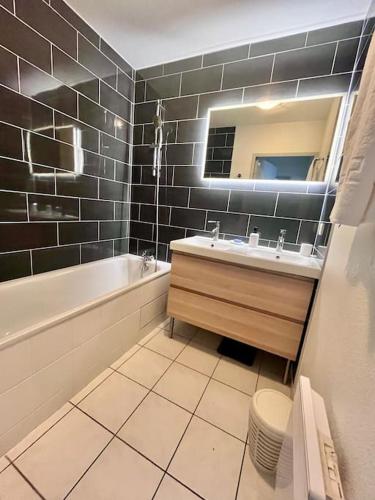 une salle de bain avec une baignoire, un lavabo et un miroir dans l'établissement Appartement T3 proche remparts, à Avignon