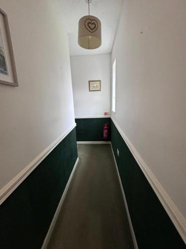 a hallway with green and white walls and a ceiling at High Trees Guest House Gatwick in Horley
